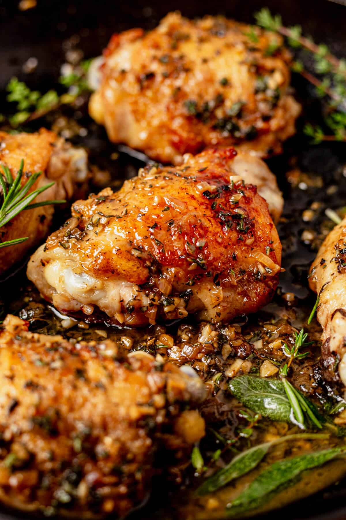 golden brown crispy chicken thighs with herbs in a cast iron skillet