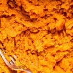 mashing cooked sweet potato in a bowl with a fork.