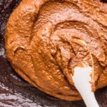 spreading frosting onto cooled chocolate potato cake.