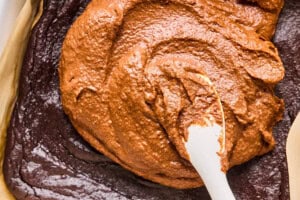 spreading frosting onto cooled chocolate potato cake.