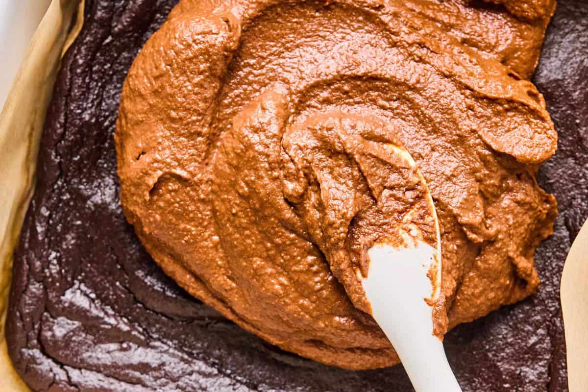 spreading chocolate frosting onto chocolate potato cake.