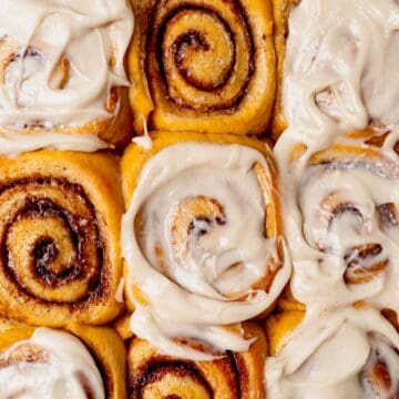 pumpkin cinnamon rolls in a pan with cream cheese frosting