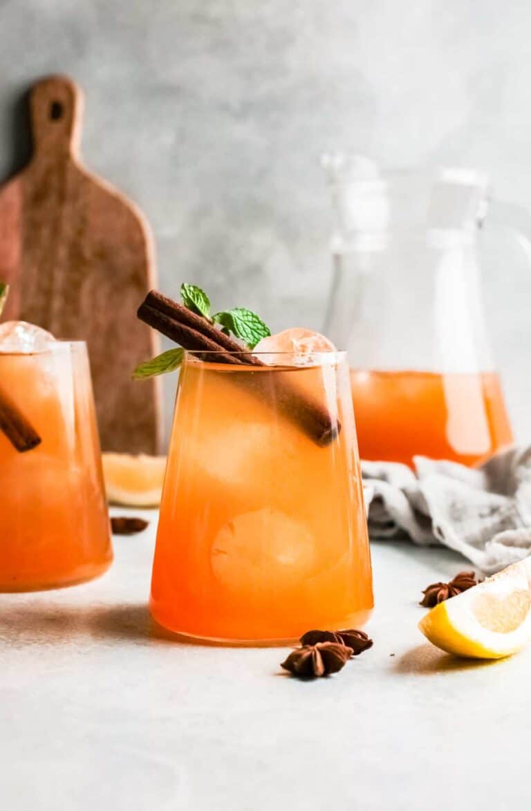 pumpkin whiskey smash cocktails on a countertop with cinnamon sticks.