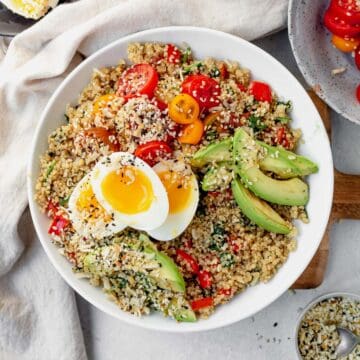 savory quinoa breakfast bowl with avocado, tomatoes and eggs