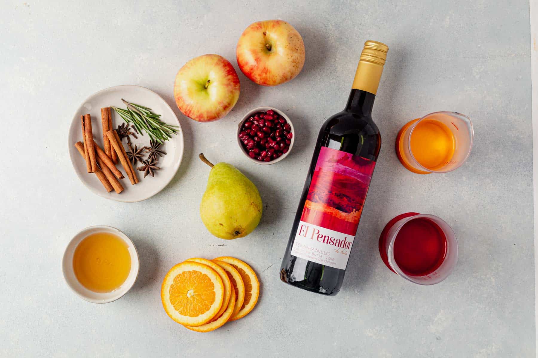 wine, oranges, pears, cinnamon sticks, orange liqueur on a table