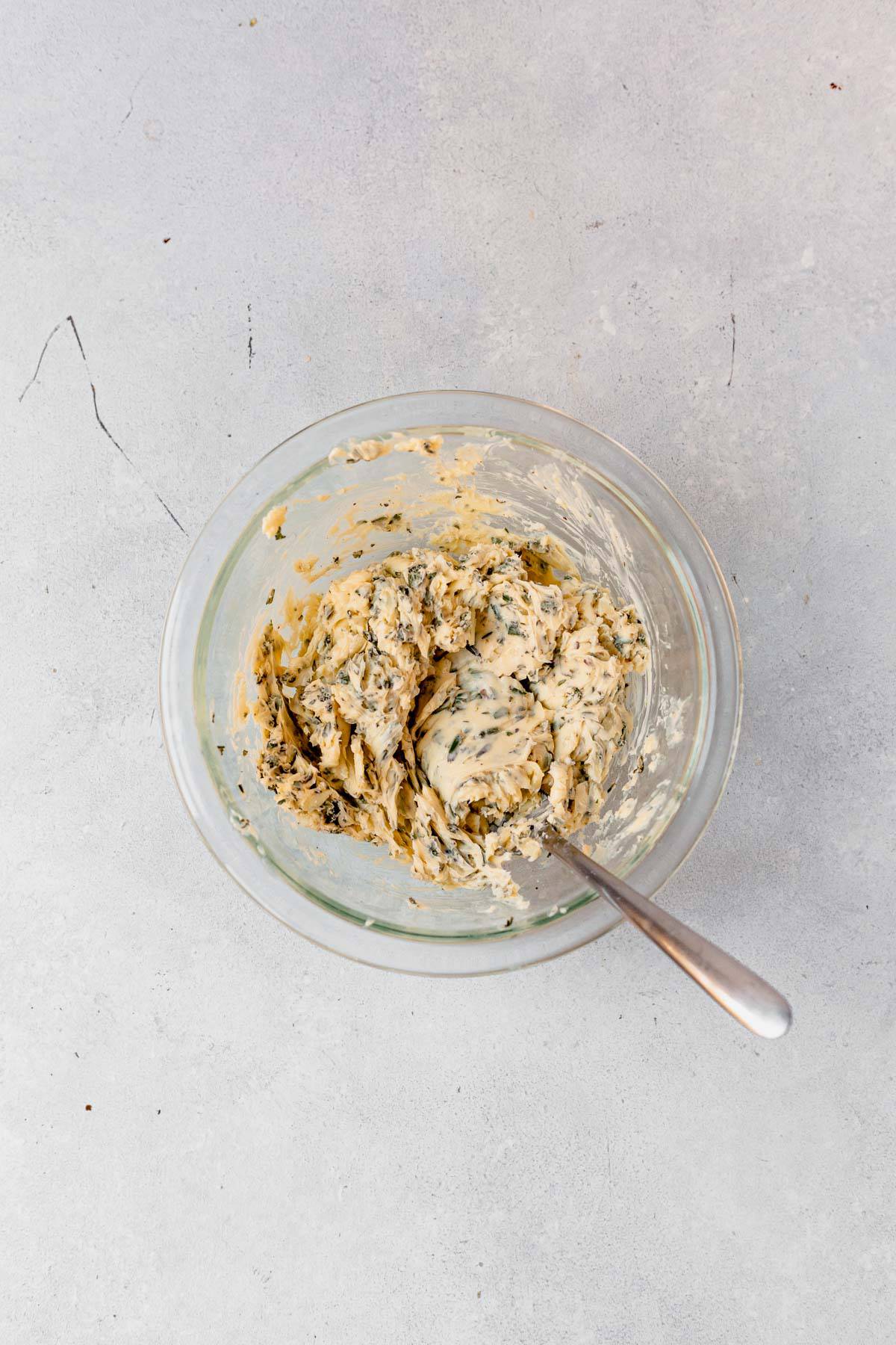 compound herb butter mixed in a dish with a spoon.