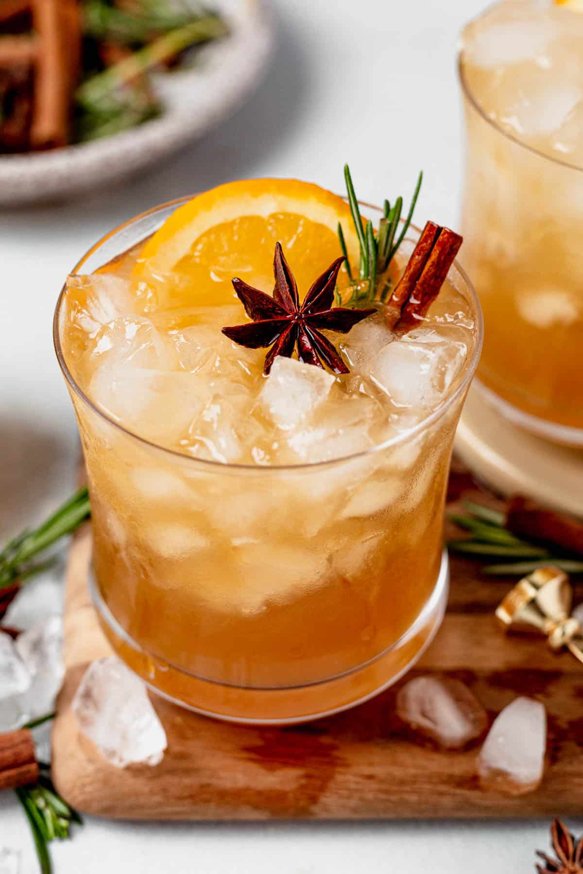 maple bourbon smash in an old fashioned glass with fresh orange and cinnamon sticks