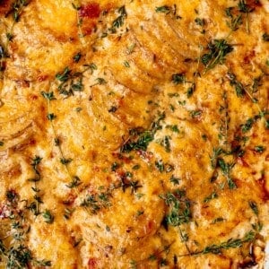 cheesy scalloped potatoes in a dish with fresh thyme on top.