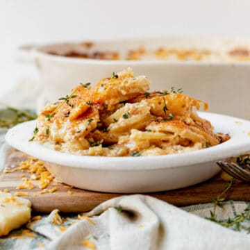 cheesy scalloped potatoes in a dish with fresh thyme