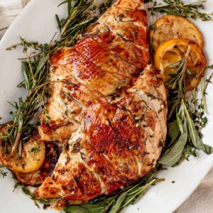 two air fryer turkey breasts on a platter with fresh herbs