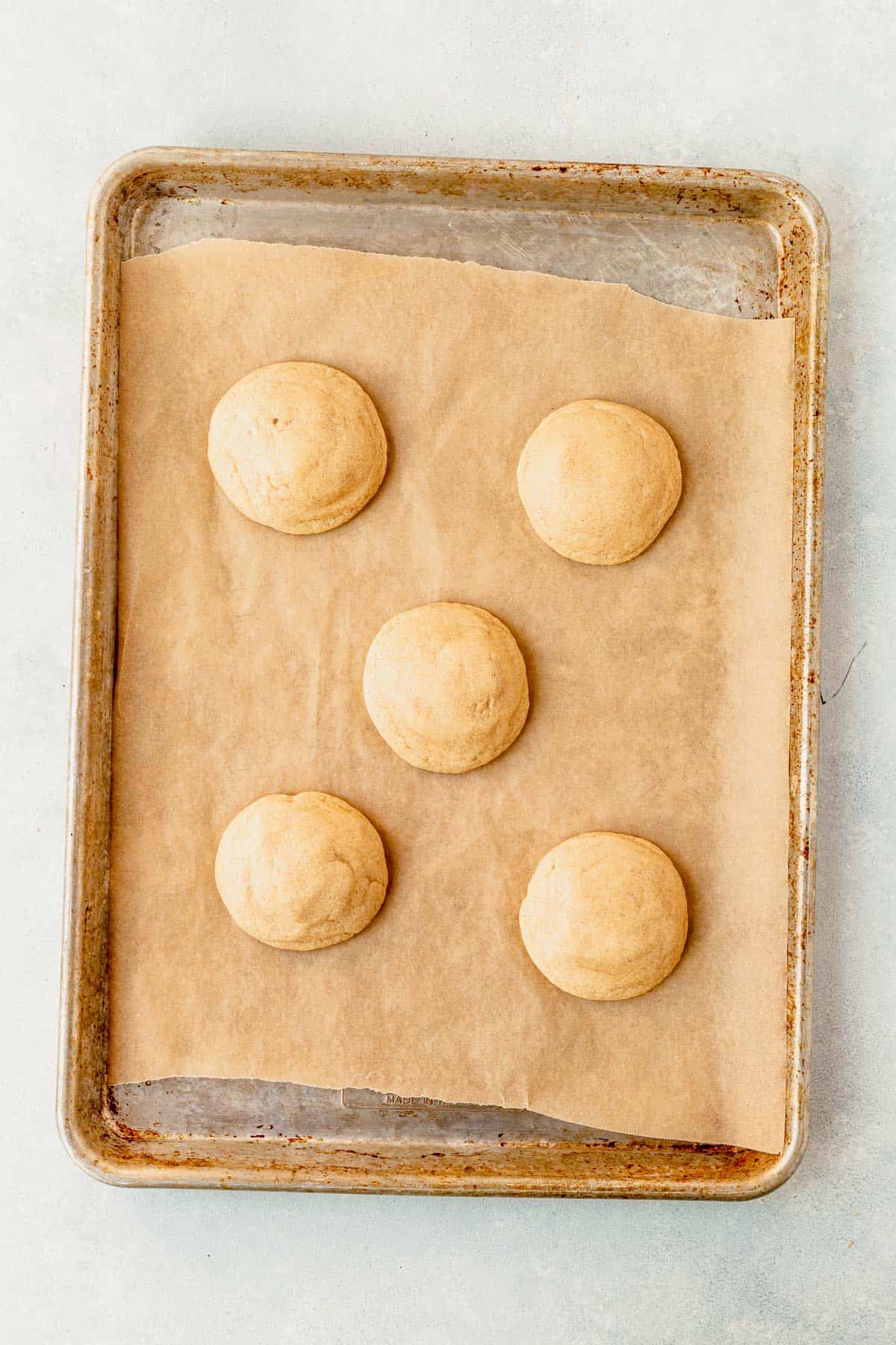baked caramel cheesecake cookies resting on a cookie sheet.
