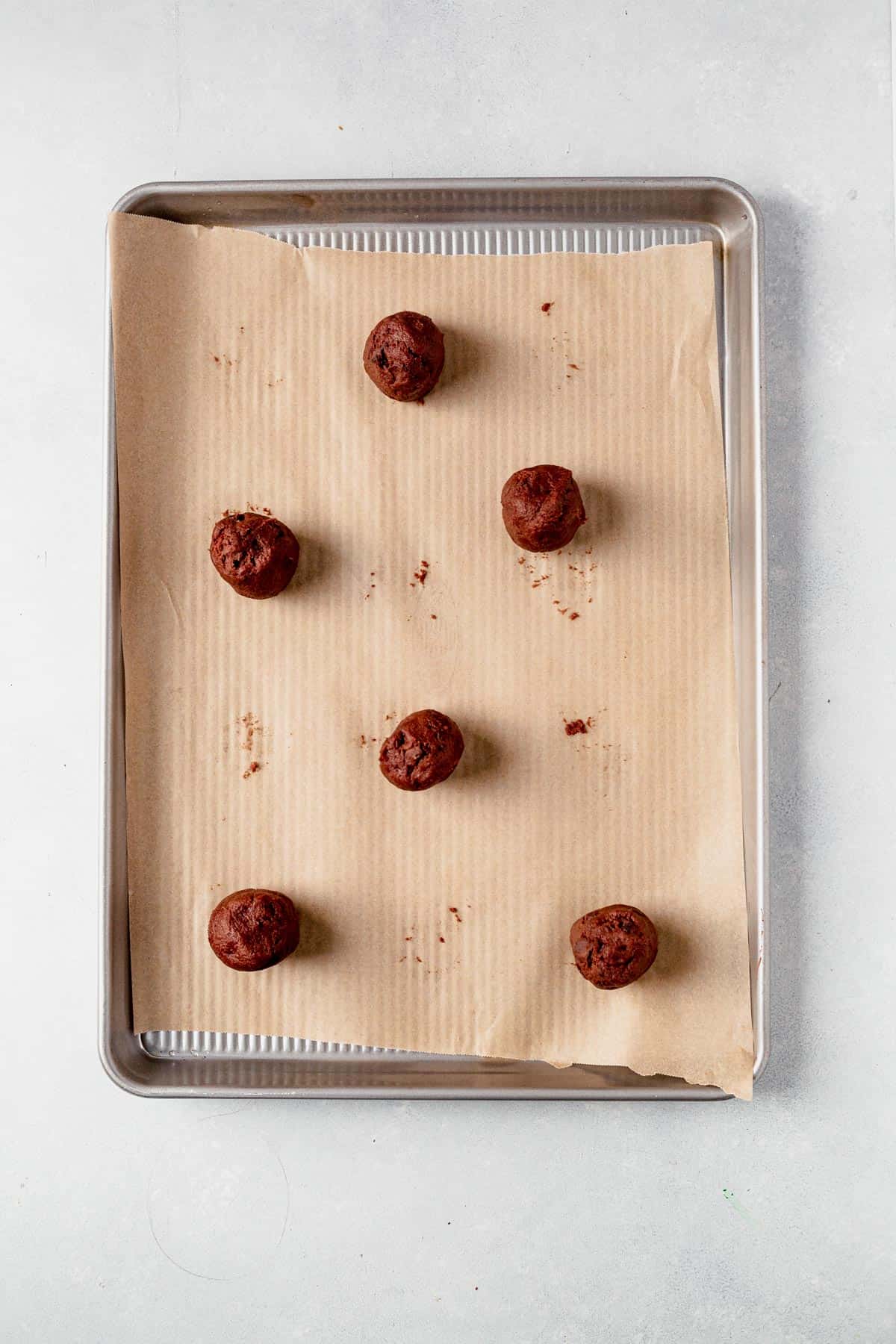 chocolate pudding cookie dough balls on a parchment lined baking sheet.