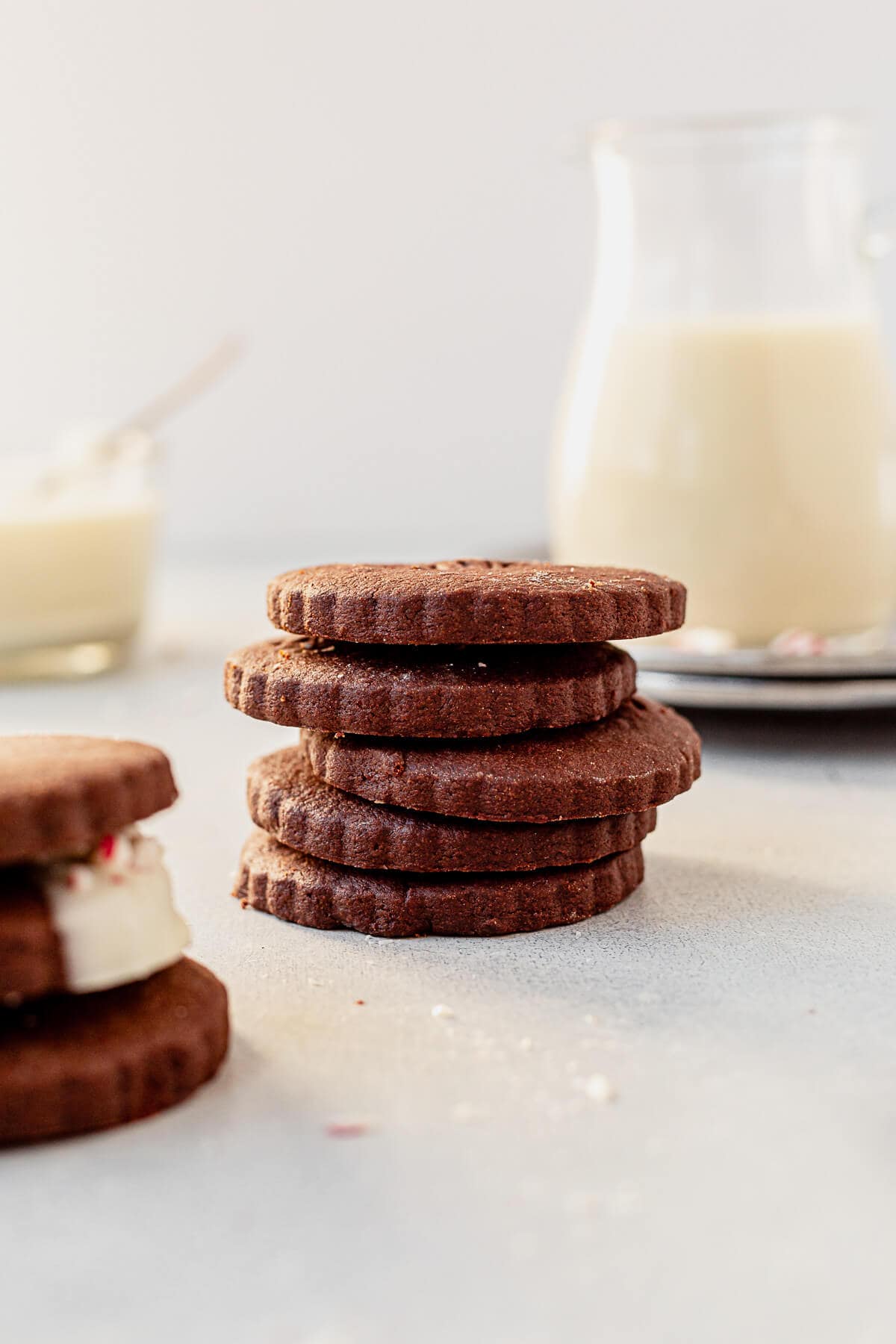 a stack of chocolate shortbread cookies with a glass of milk
