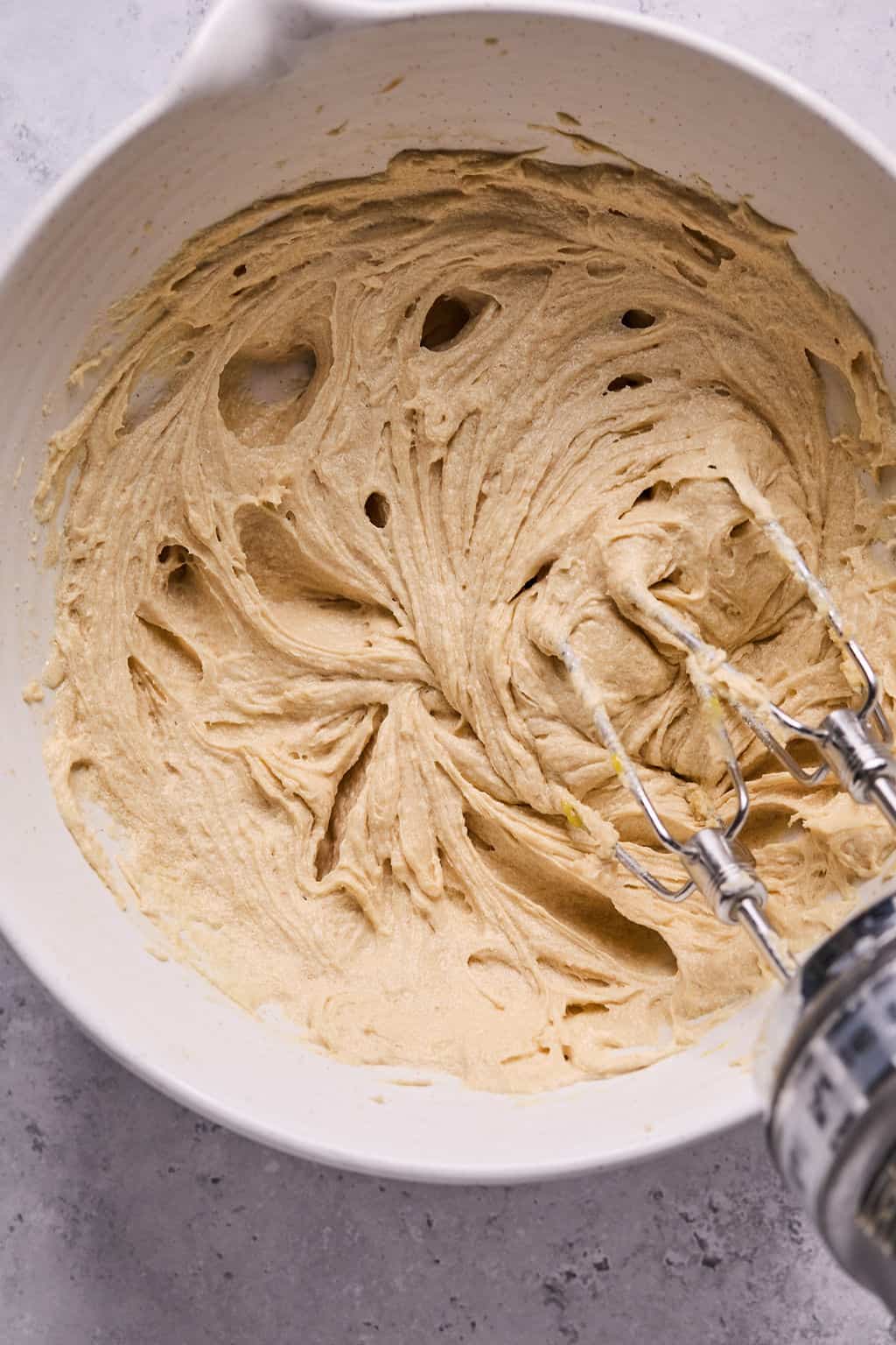 wet ingredients for cookie dough in a bowl with an electric mixer.