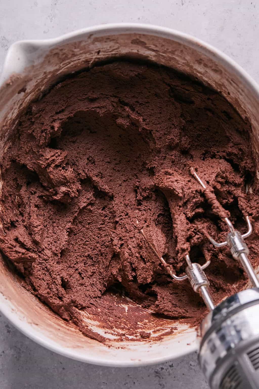 chocolate cookie dough in a bowl with an electric mixer.