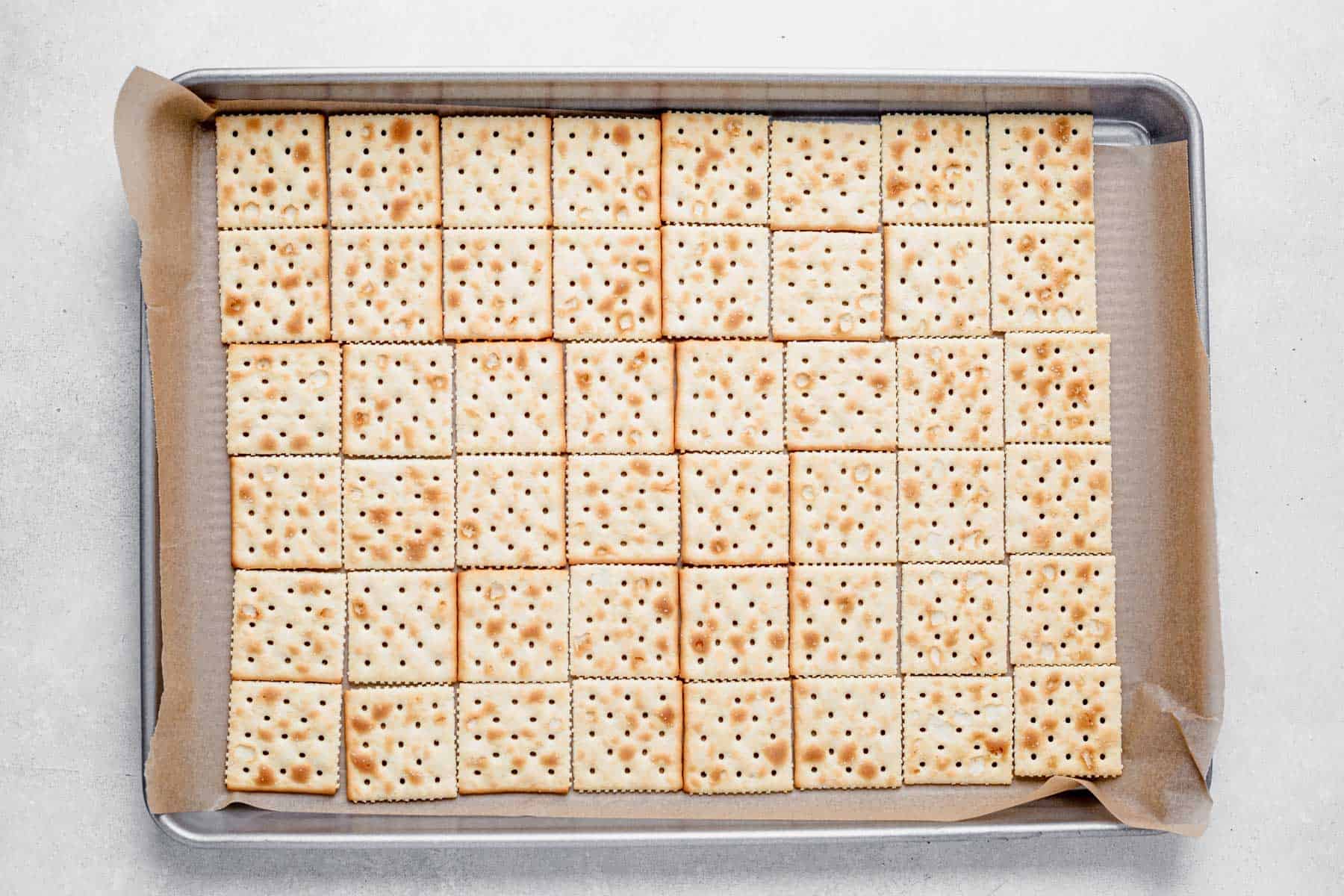 saltine crackers lined in a sheet pan with parchment paper