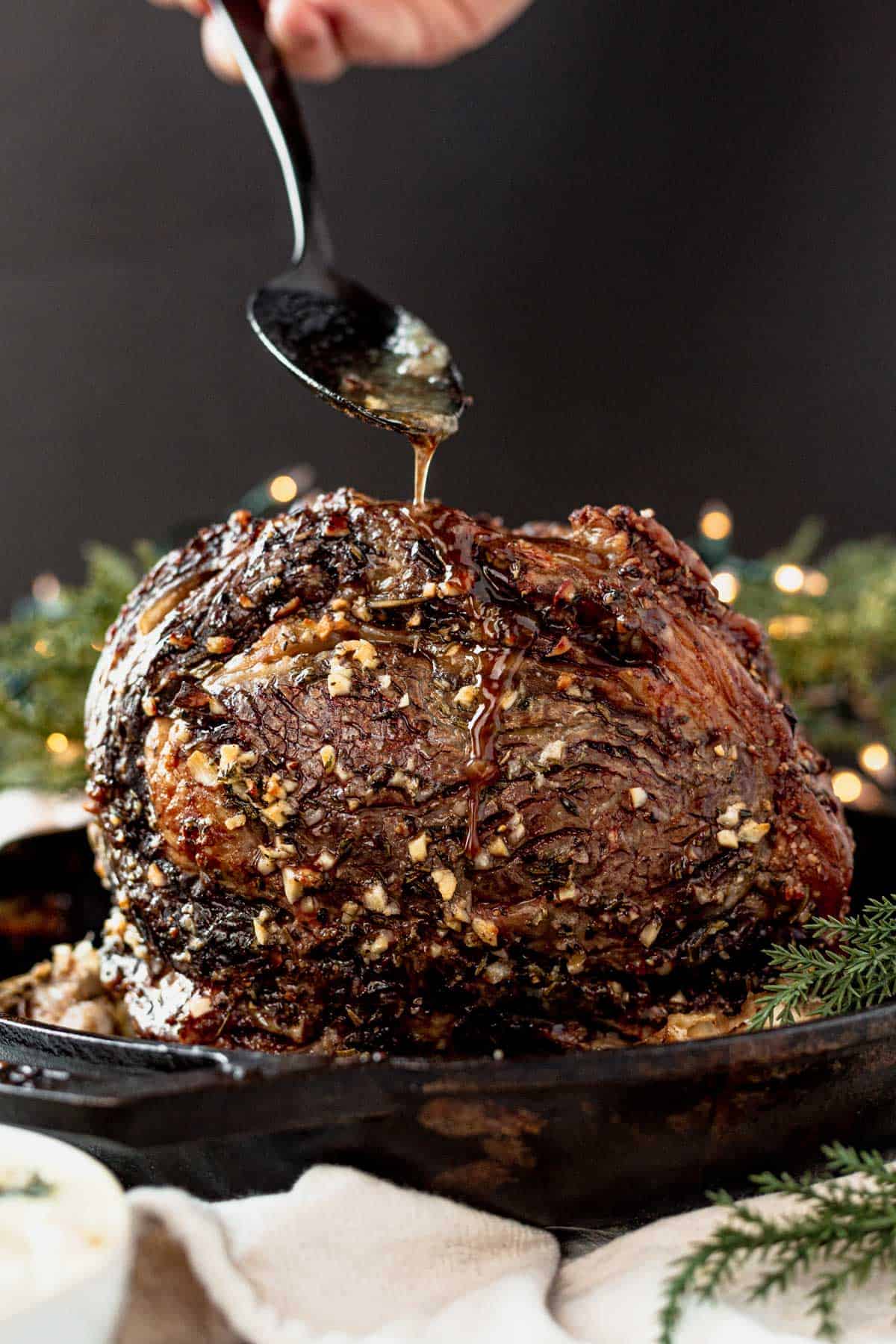 pouring au jus over a standing rib roast