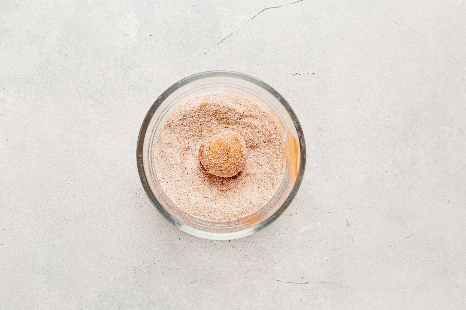 chai cookie dough ball rolling in chai sugar.