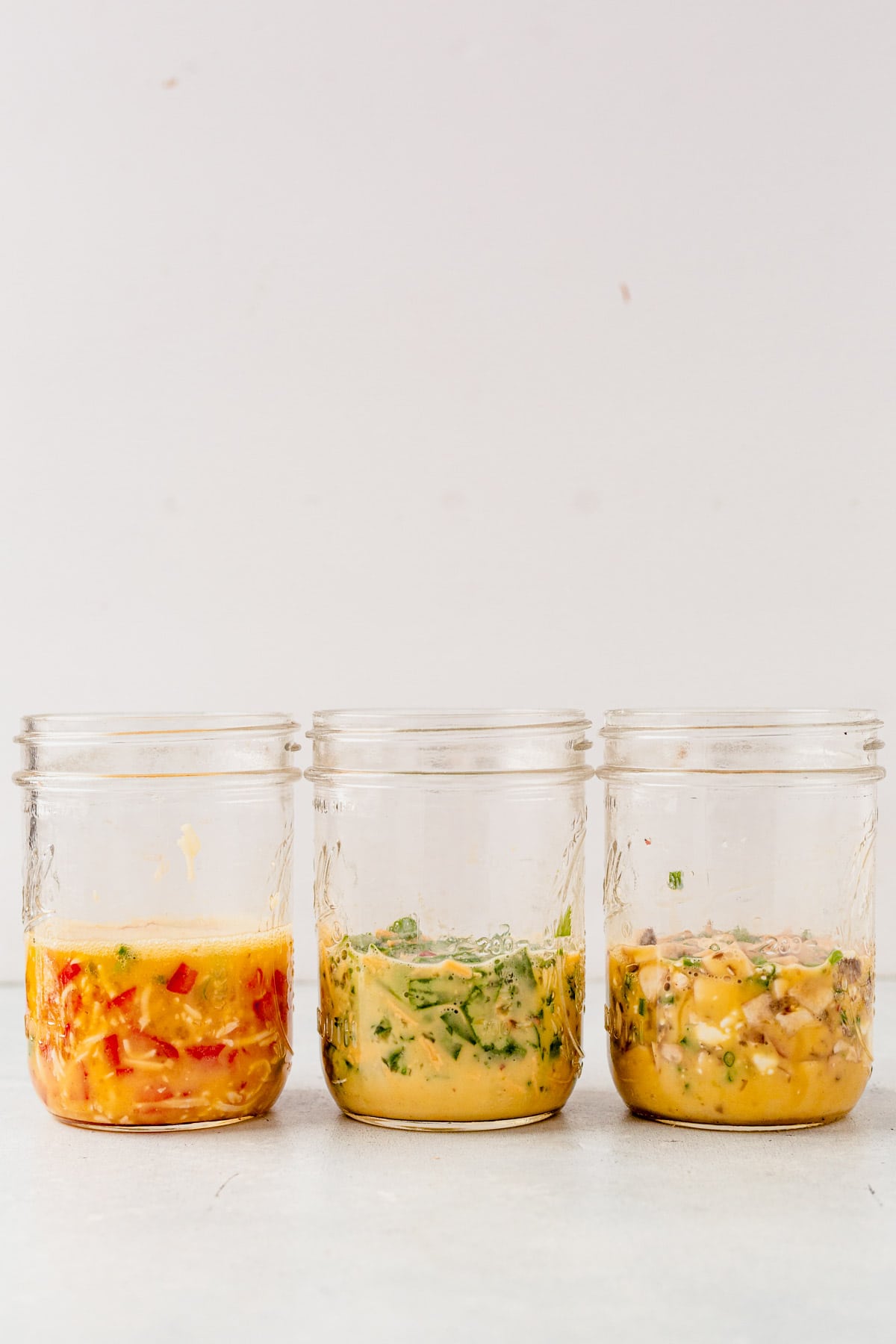 mason jars filled with veggies, cheese and eggs