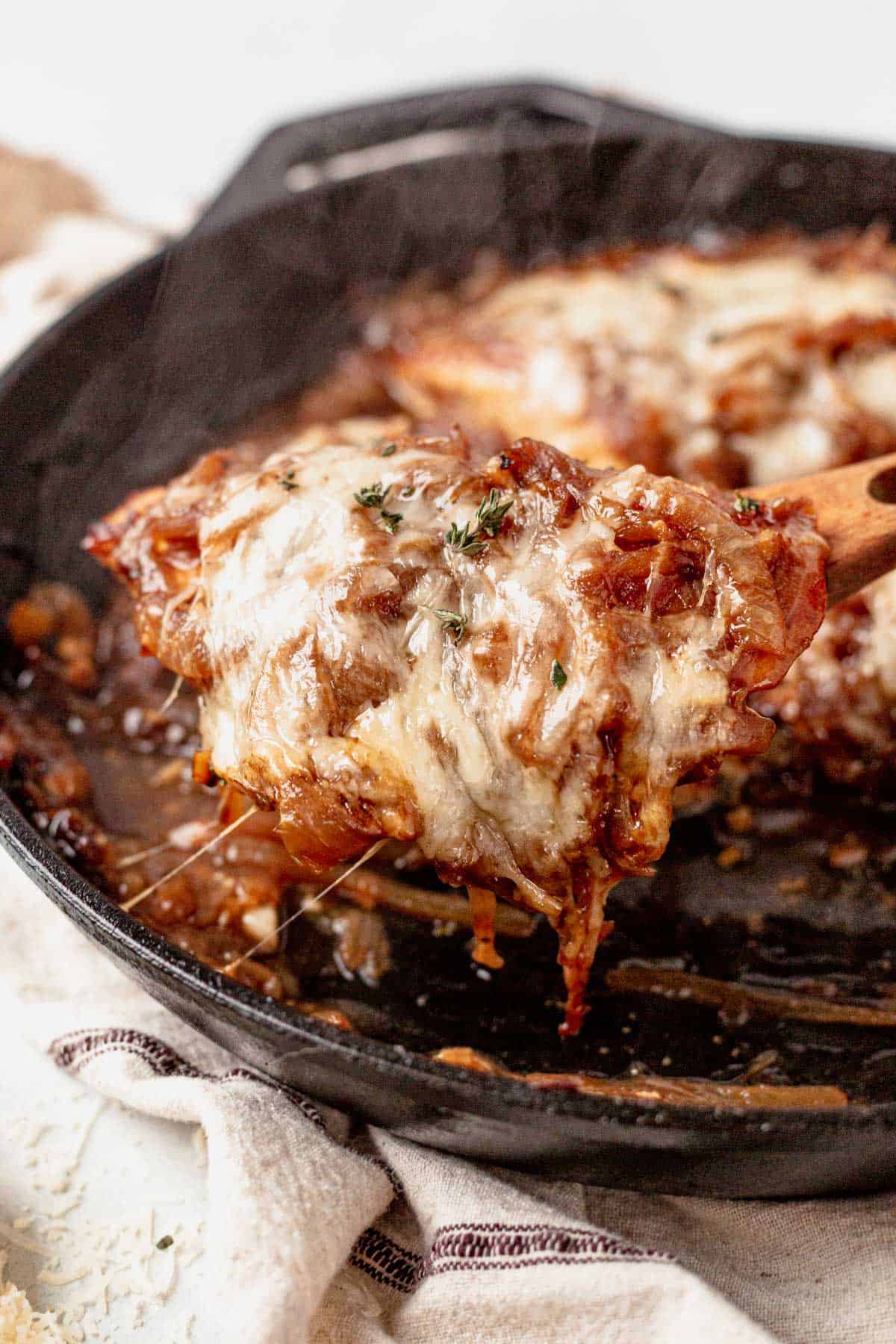 pulling french onion baked chicken out of a skillet