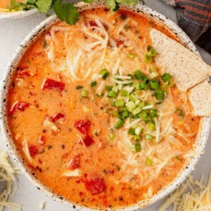 a bowl of buffalo chicken chili with shredded cheese, green onions, and tortilla chips.