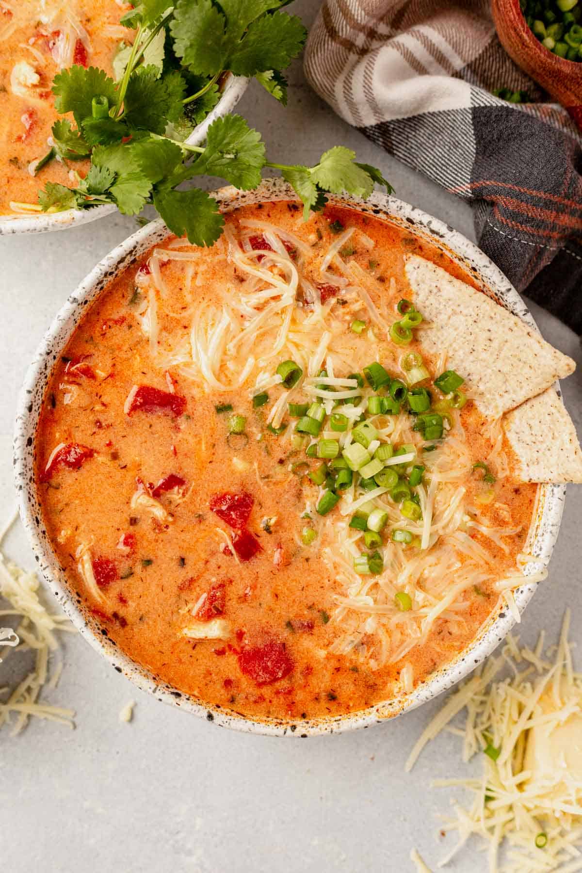 slow cooker buffalo chicken chili in a bowl with cheese, green onion, and tortilla chips.