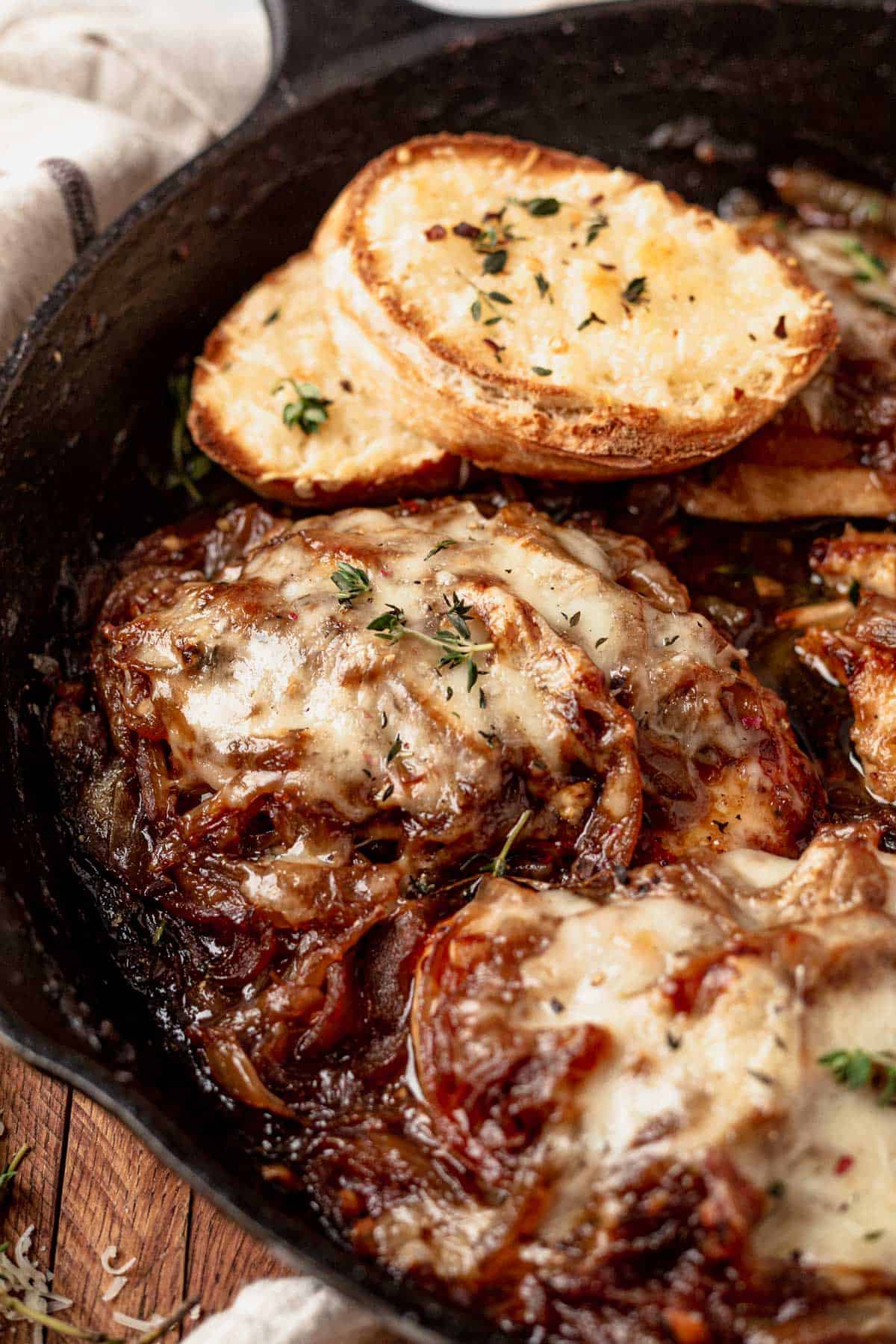 a piece of french onion baked chicken in a skillet with crusty bread
