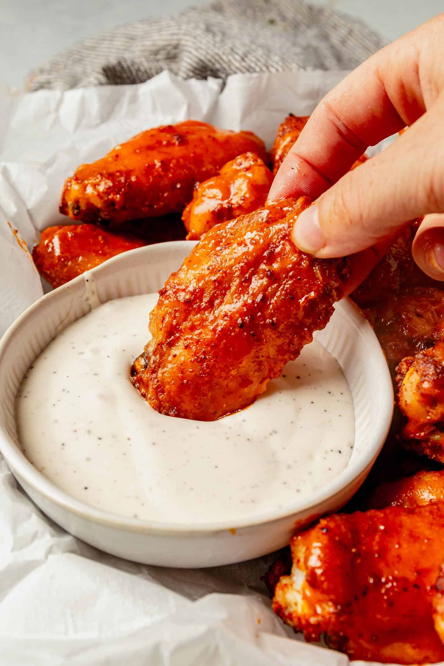 dipping a chicken wing in a bowl of ranch