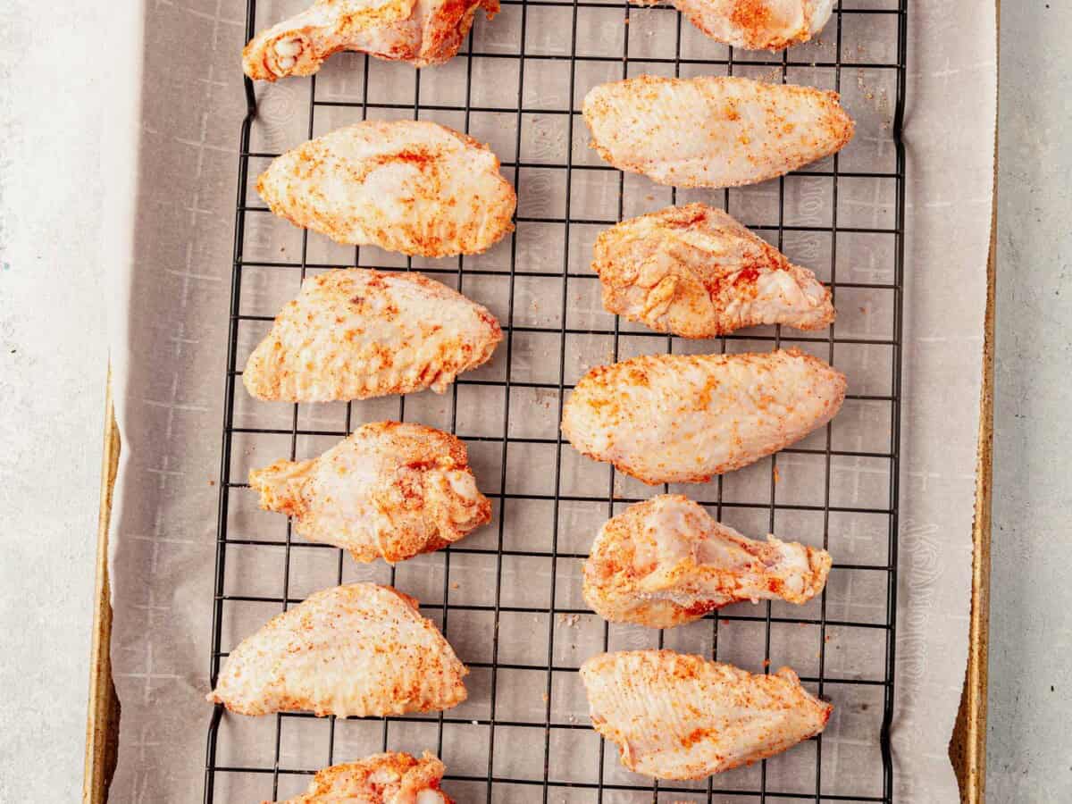 unbaked chicken wings on a wire rack on top of a baking sheet