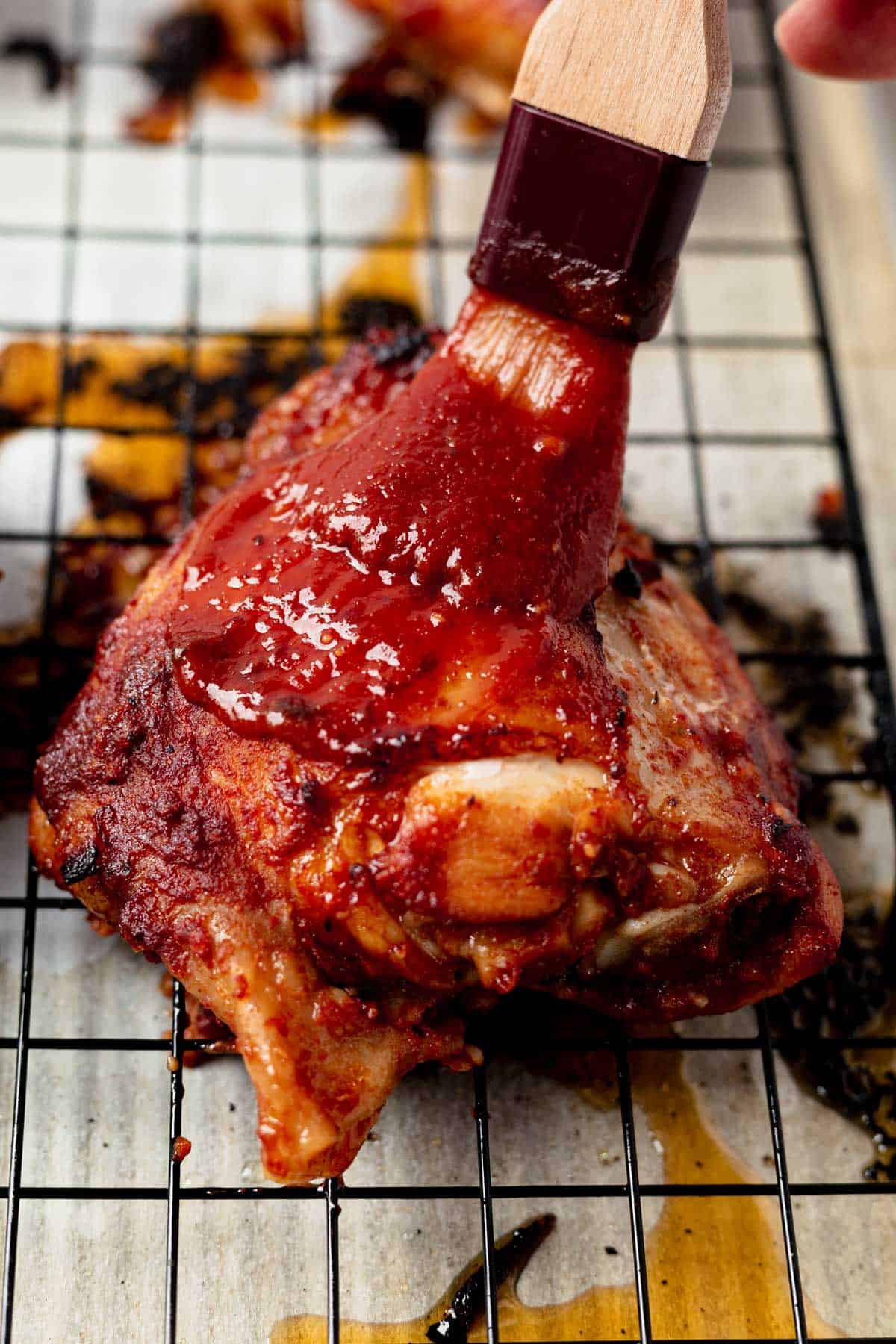 brushing bbq sauce onto baked chicken thighs