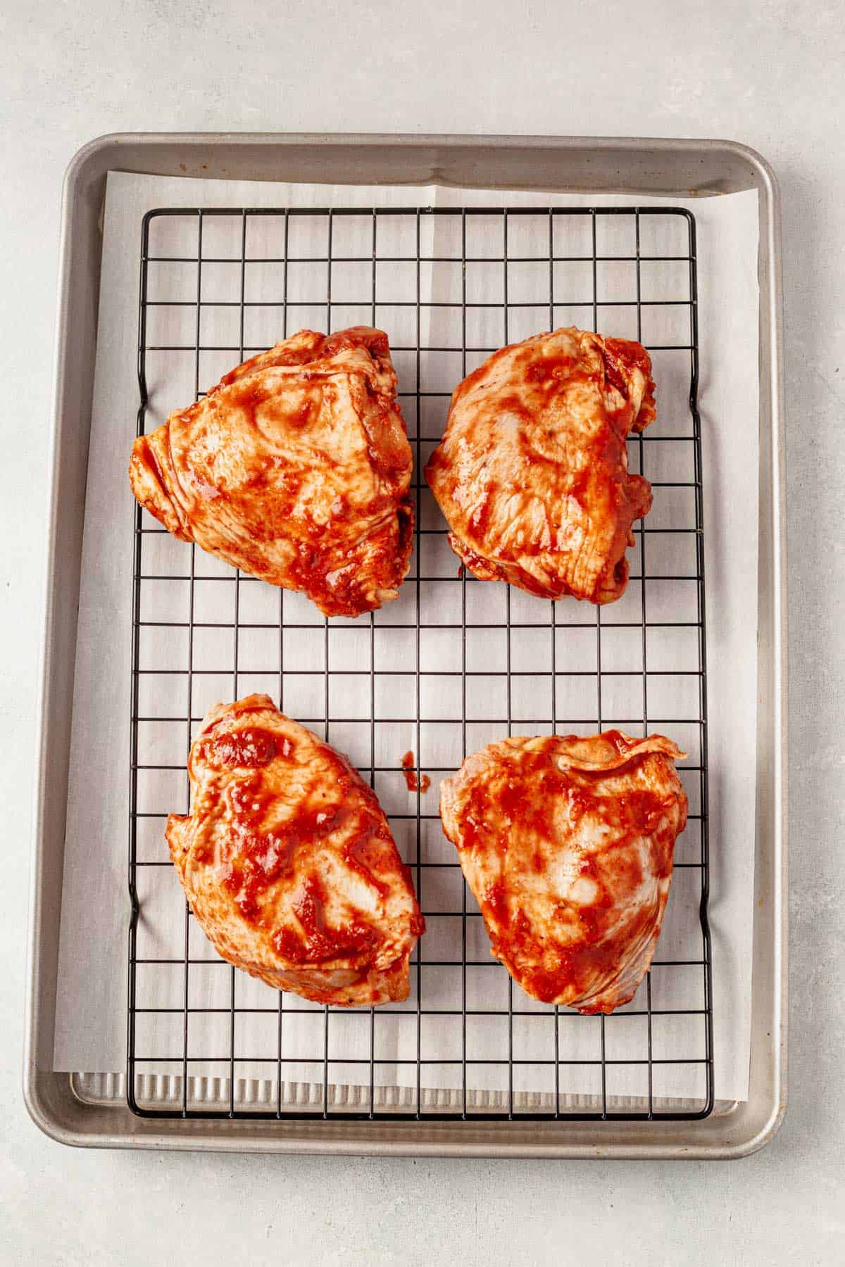 unbaked bbq chicken thighs on a baking sheet