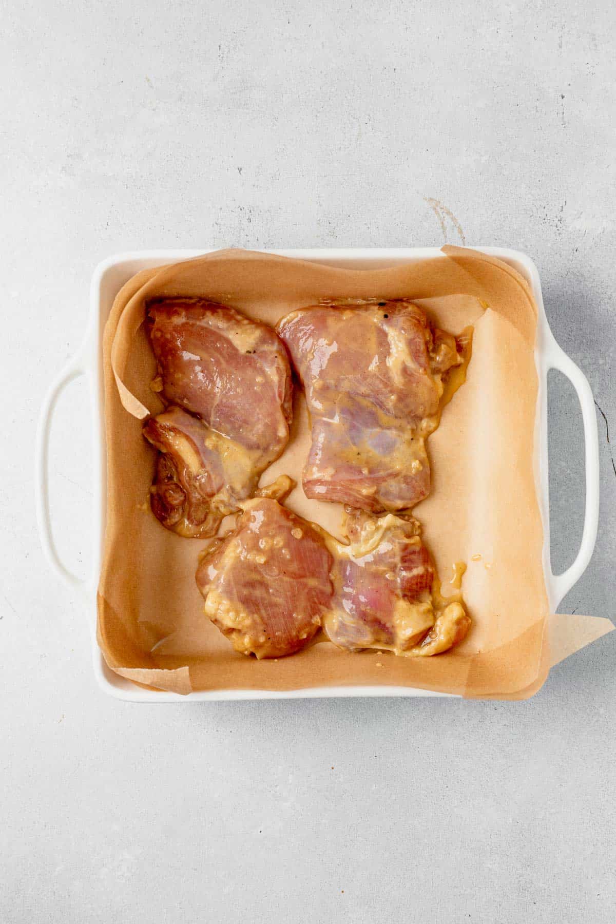 raw chicken thighs in a baking dish with honey mustard sauce