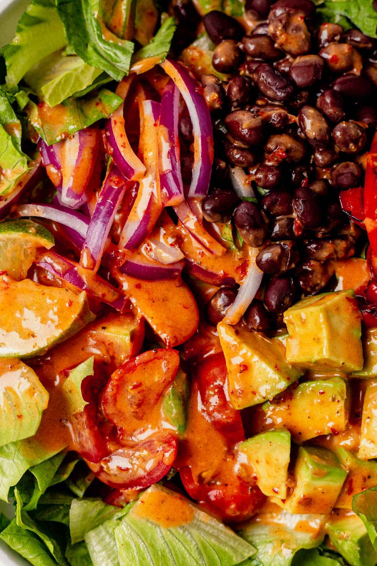 chipotle vinaigrette covering a salad with romaine, black beans, and avocado