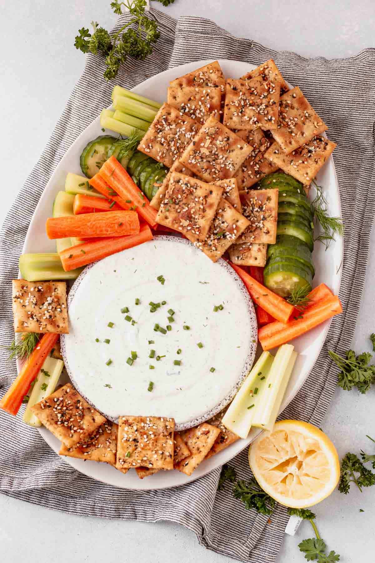 a platter of crackers and veggies with cottage cheese dip