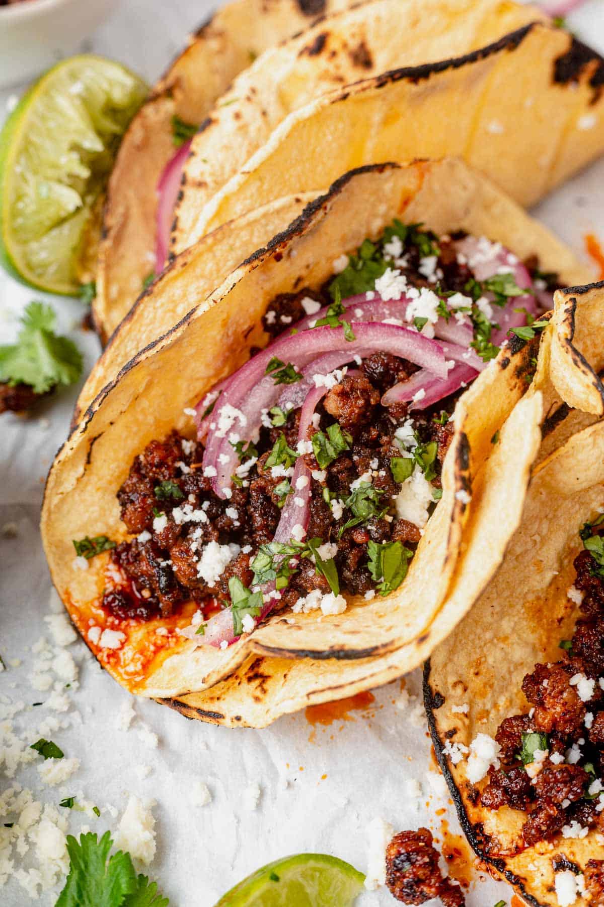 three ground pork tacos with pickled onion and cilantro