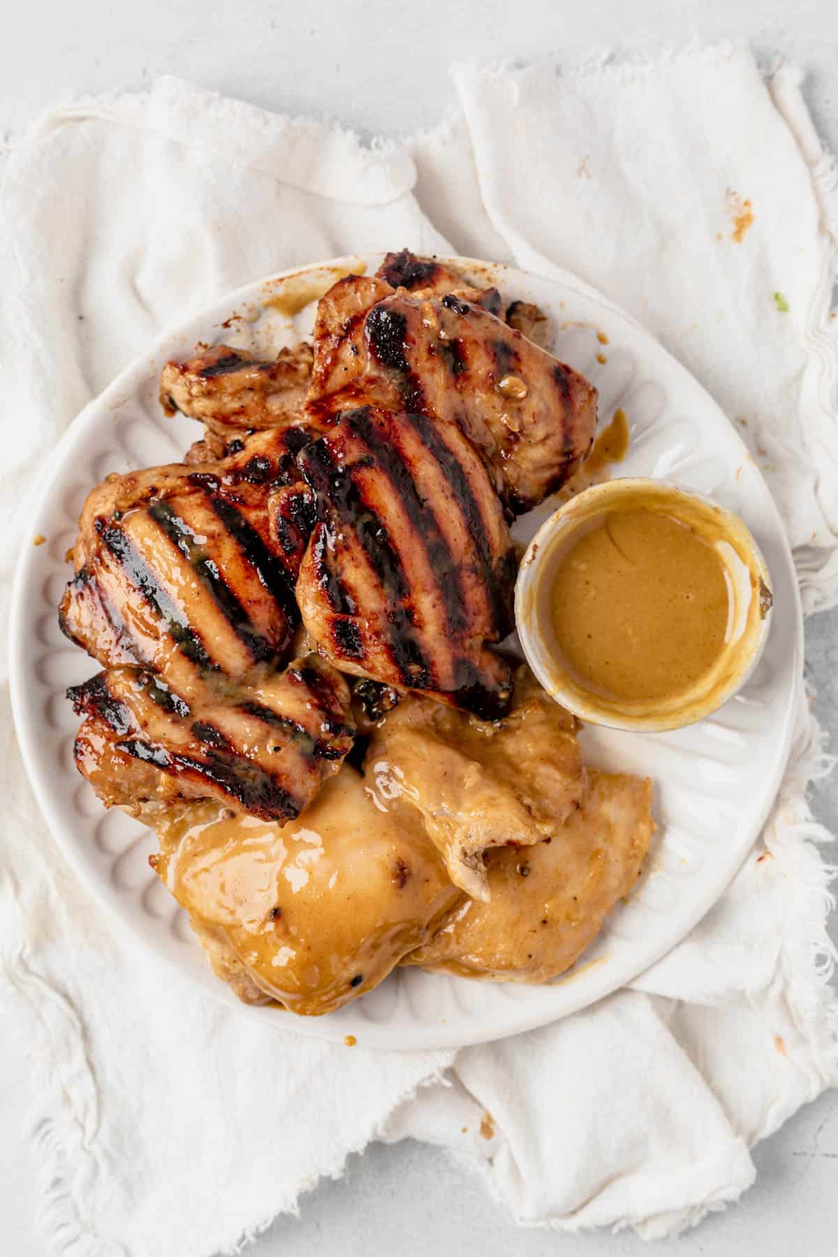 honey mustard chicken thighs on a plate with extra honey mustard sauce