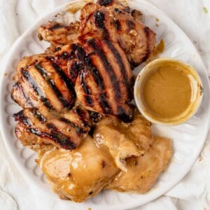 a plate of honey mustard chicken thighs with honey mustard sauce on the side