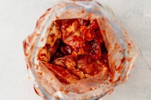 chicken thighs marinating in bbq sauce and spices in a freezer bag.