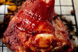 brushing bbq sauce onto baked bbq chicken thighs.
