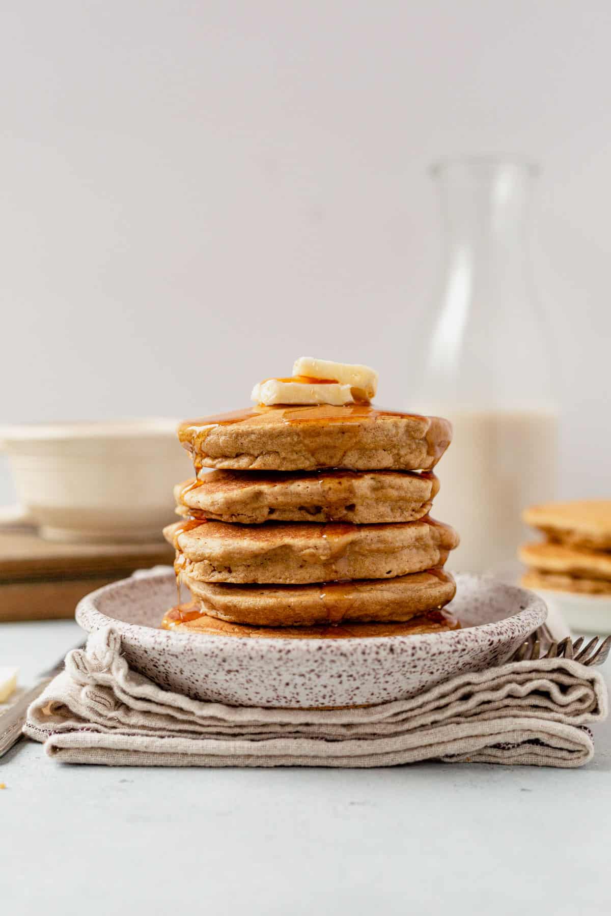 a stack of oat flour pancakes with a cup of coffee