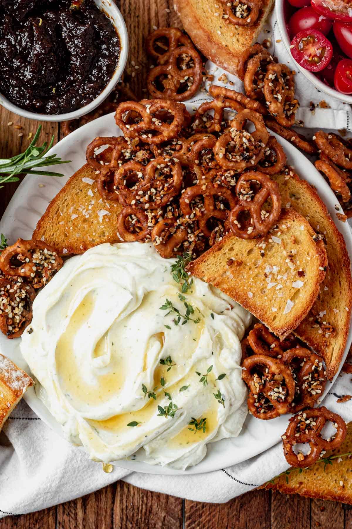 whipped goat cheese with honey and herbs in a serving dish with bread and pretzels