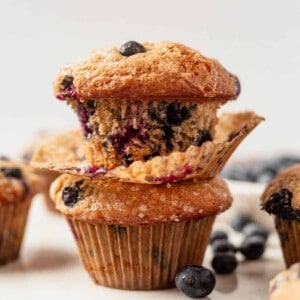 two golden brown blueberry banana muffins with fresh blueberries