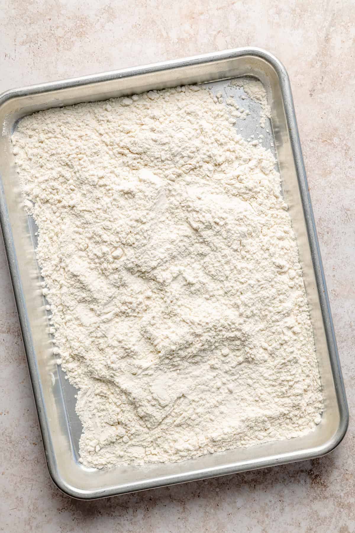 heat treated flour spread out on a large baking sheet to cool.