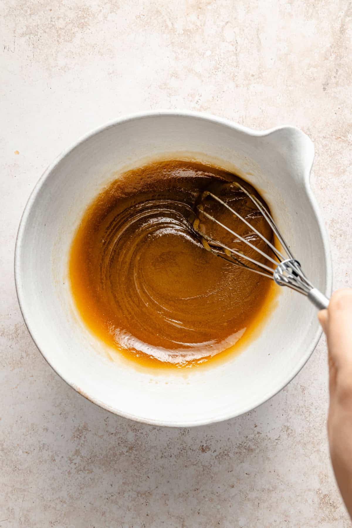 whisking wet ingredients for edible brownie batter in a mixing bowl.
