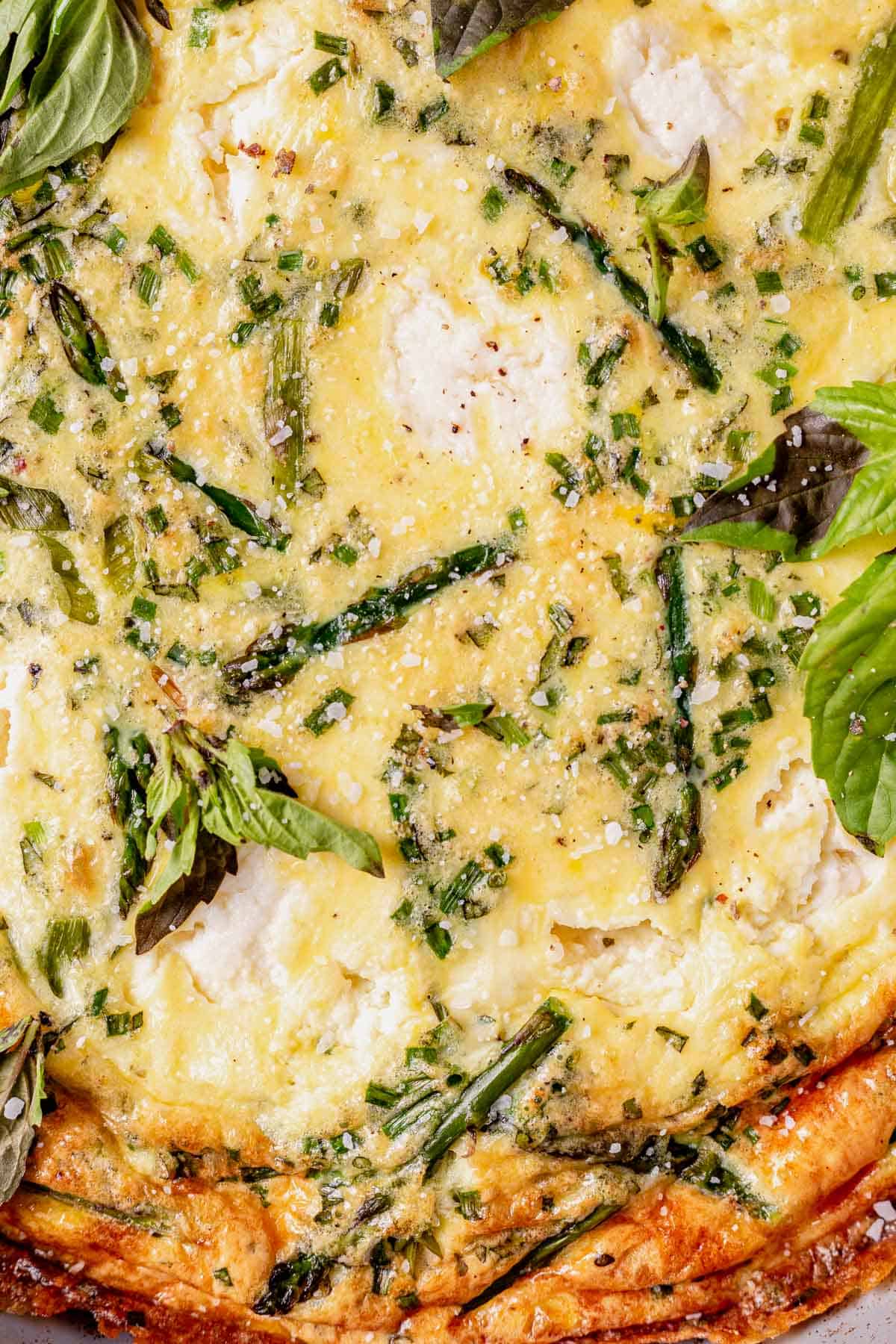 baked asparagus frittata with chopped asparagus and ricotta cheese on top