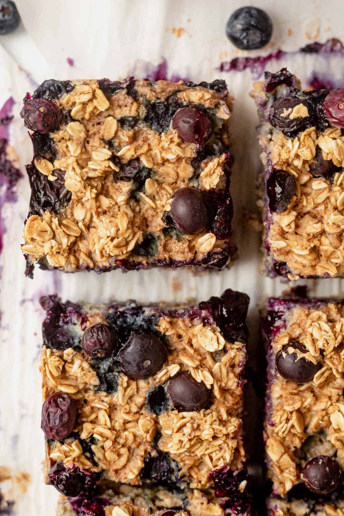 a piece of baked oatmeal with fresh blueberries on parchment paper