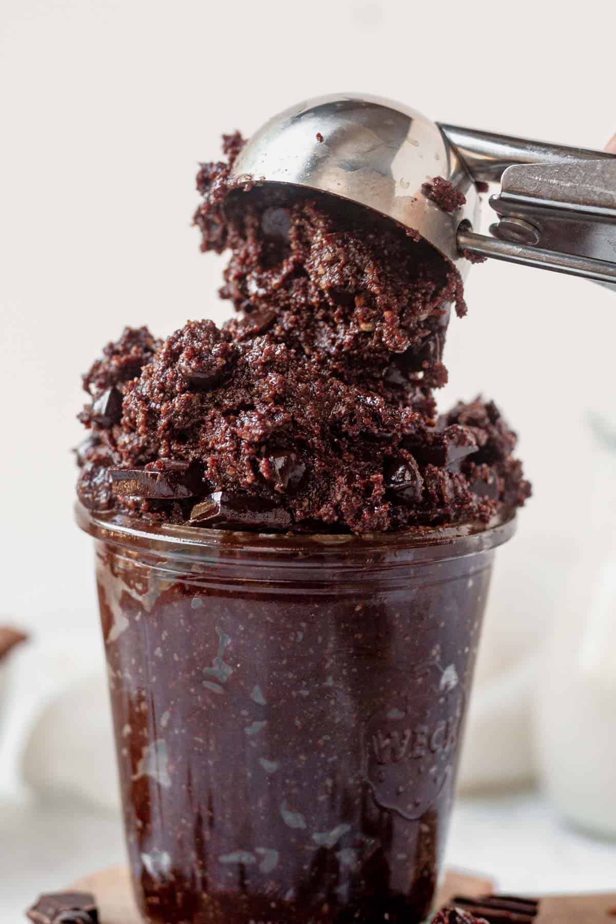 scooping edible brownie batter into a jar