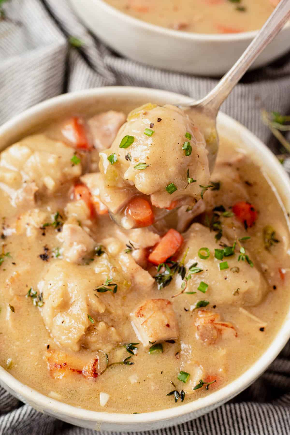 scooping a bite of gluten-free chicken and dumplings out of a bowl