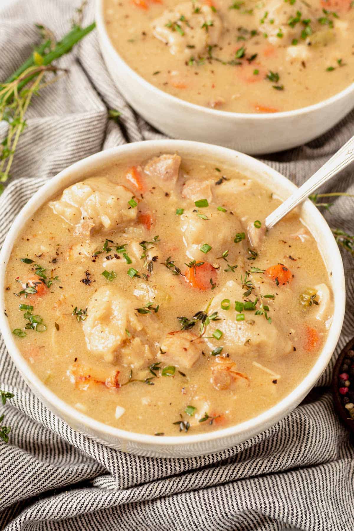 two bowls of gluten-free chicken and dumplings with fresh herbs