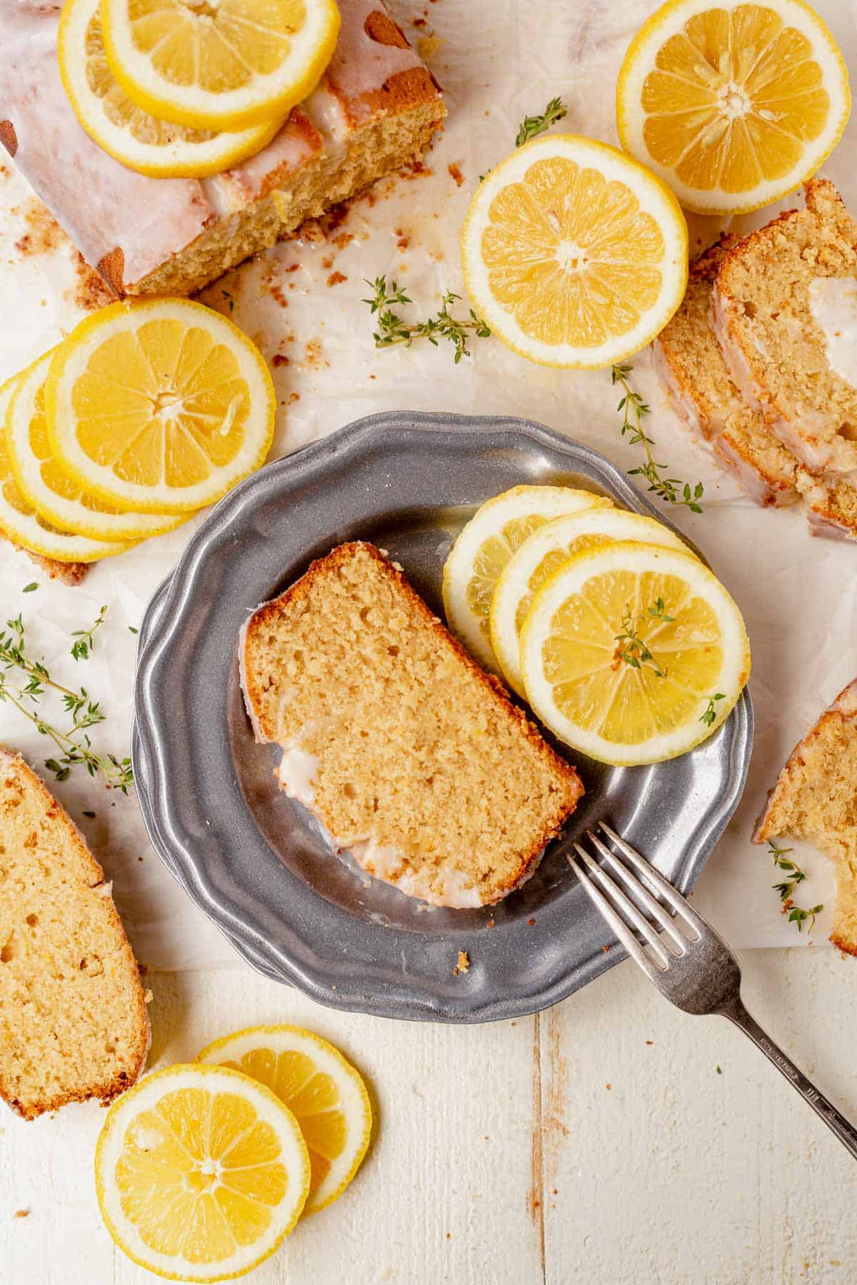 a piece of gluten-free lemon drizzle cake on a plate with lemon slices